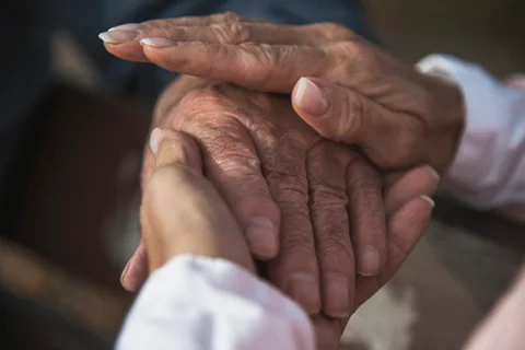 A pair of hands, both people of color, holding each other in a comforting embrace
